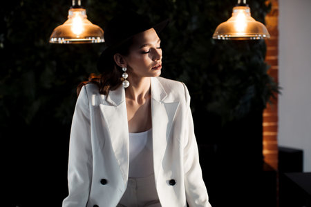 Young girl in a white suit and a black hat. The concept of clothing.
