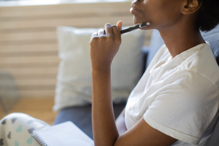 African American girl writes in a notebook in a cozy room