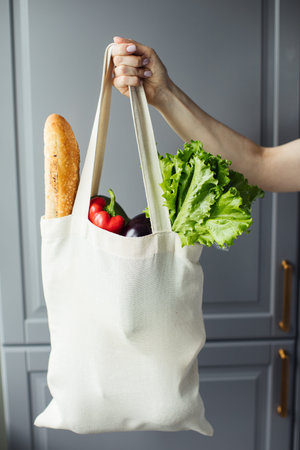 Female hand with eco bag on grey backgroundの写真素材