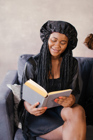 Three African American girl sitting on the couch reading a book