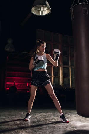 cool female fighter in boxing gloves trains in the gym. Mixed martial artsの写真素材