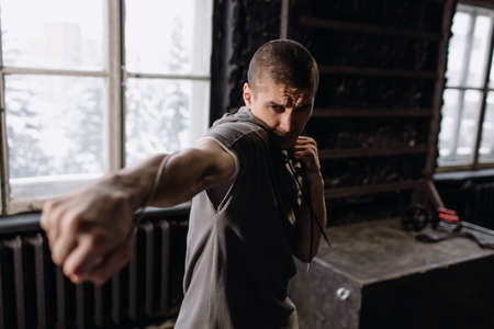 Cool man fighter in boxing bandages trains in the gym. Mixed martial artsの写真素材