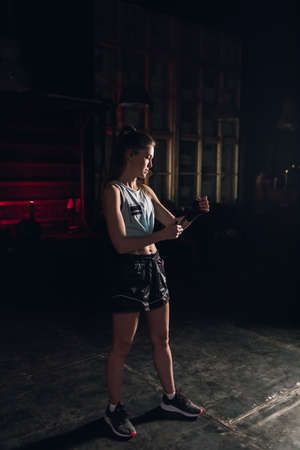 Cool female fighter in boxing bandages trains in gym. Mixed martial artsの写真素材