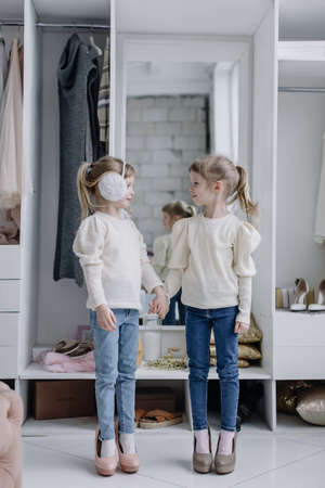 Girls sisters stand in a modern dressing room and look at the cameraの写真素材