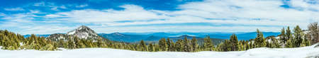 Mountains, lakes, and a forest with snow - photographed as a wide panorama at Lassen Volcanic National Park in Northern Californiaの写真素材