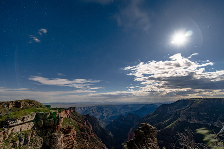 The Grand Canyon at night, with the moon and stars behind thin cloudsの写真素材
