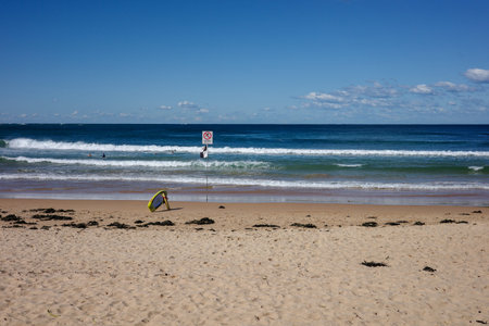Sandy beach on a sunny day with a surfboard in the foregroundの写真素材