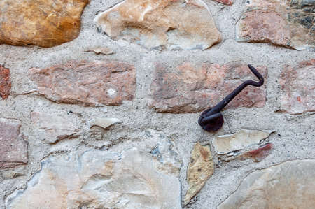Typical wall made of stones and bricks of ancient Italian house, with rusty iron door hook.の写真素材