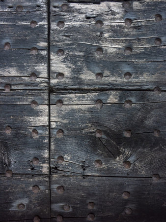 Antique door with wooden plank panels of a rural house, with iron fixing parts, Italy.の写真素材