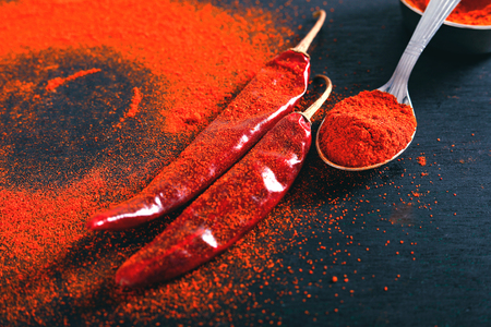Red Chili pepper flakes and chili powder burst on black backgroundの写真素材