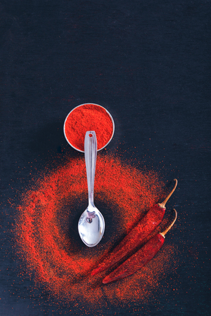 Red Chili pepper flakes and chili powder burst on black backgroundの写真素材