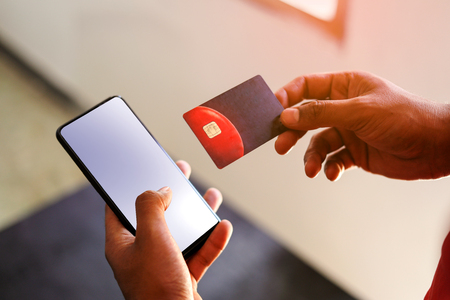 Hand holding credit card and mobile phone with black and white background.の写真素材