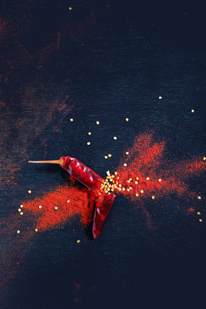 Red Chili pepper flakes and chili powder burst on black backgroundの写真素材