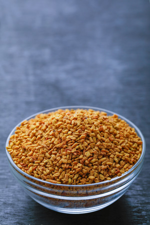 fenugreek seeds in glass bowl on wooden backgroundの写真素材