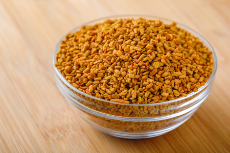 fenugreek seeds in glass bowl on wooden backgroundの写真素材