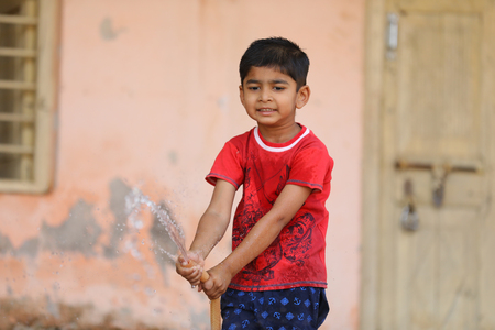 indian child playing with water tubeの写真素材