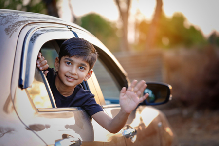 Cute Indian Child waving from car windowの写真素材