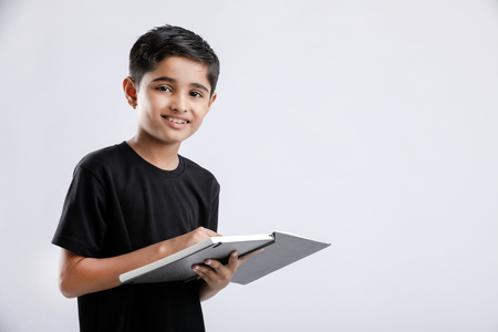 Cute little Indian / Asian boy reading book isolated over white backgroundの写真素材
