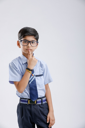 Cute little indian school boy asking / posing to keep silence, standing isolated over white backgroundの写真素材