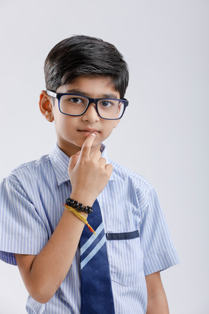 Cute little indian school boy asking / posing to keep silence, standing isolated over white backgroundの写真素材
