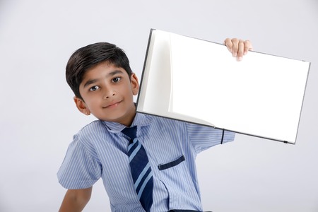 Cute little Indian/Asian school boy showing note book over white backgroundの写真素材
