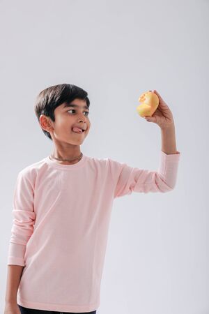 Cute indian/Asian little boy eating Mango with multiple expressions. isolated over white backgroundの写真素材