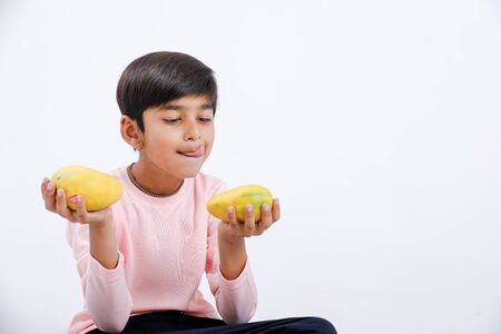 Cute indian/Asian little boy eating Mango with multiple expressions. isolated over white backgroundの写真素材