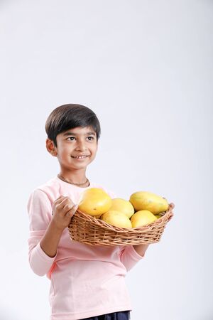 Cute indian/Asian little boy holding Mango basket in hand and giving multiple expressions. isolated over white backgroundの写真素材
