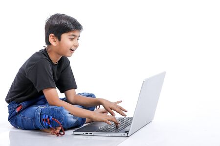 Cute little Indian/Asian boy studying or playing game with laptop computerの写真素材