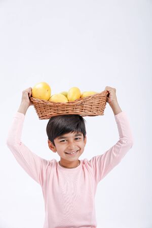 Cute indian/Asian little boy holding Mango basket in hand and giving multiple expressions. isolated over white backgroundの写真素材