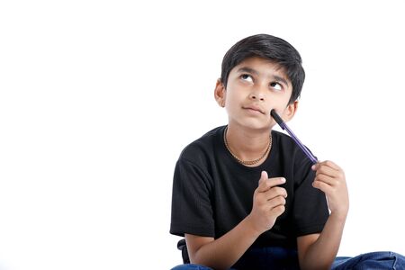 Cute Indian boy thinking idea and looking at up, isolated on white backgroundの写真素材