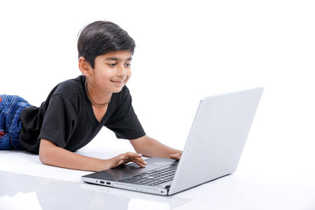 Cute little Indian/Asian boy studying or playing game with laptop computer