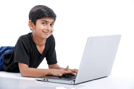 Cute little Indian/Asian boy studying or playing game with laptop computerの写真素材