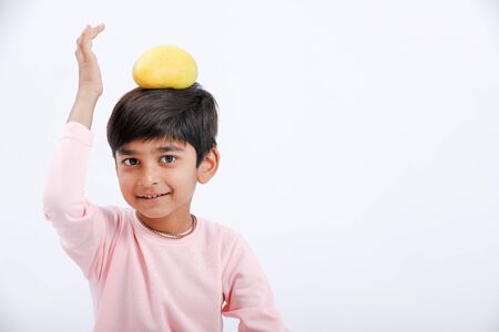 Cute indian/Asian little boy eating Mango with multiple expressions. isolated over white backgroundの写真素材