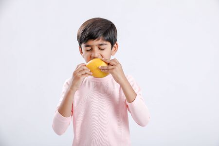Cute indian/Asian little boy eating Mango with multiple expressions. isolated over white backgroundの写真素材