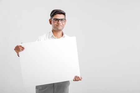 Young Indian business executive showing blank sign board over white backgroundの写真素材