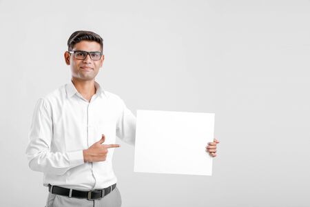 Young Indian business executive showing blank sign board over white backgroundの写真素材