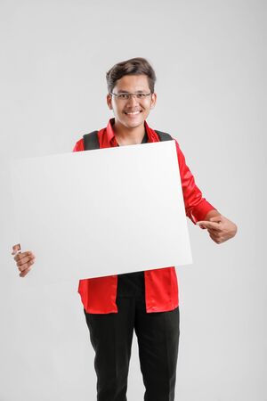 Handsome Indian/Asian Male college student showing blank signboardの写真素材