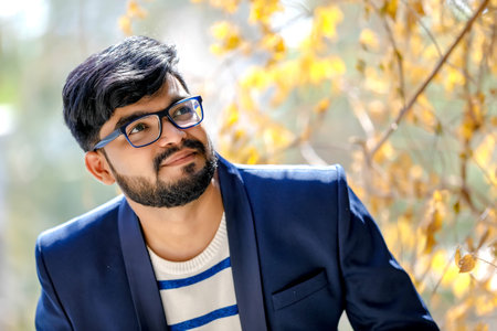 Portrait of a young Indian successful businessman wearing suit over wall background