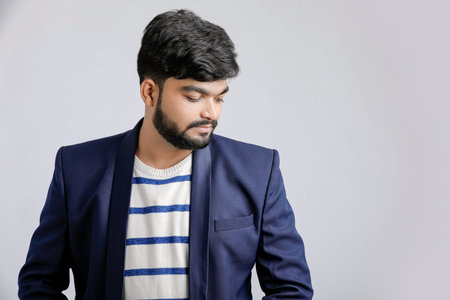 Portrait of a young Indian successful businessman wearing suit over white background