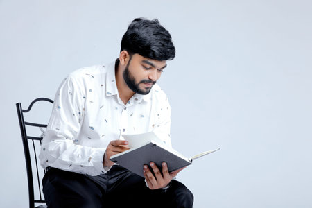 Handsome young man wearing a classic outfit, holding file reading it and smiling, isolated on white background.の写真素材