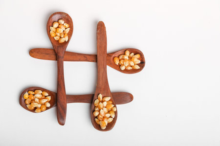 Dried corn seeds in spoon on white background