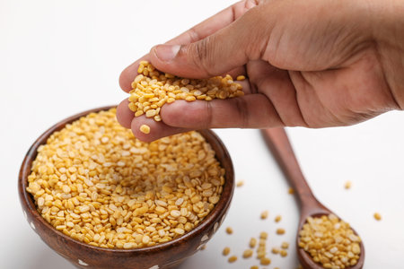 yellow moong mung dal lentil pulse bean in hand on white background