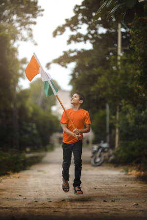 little indian child holding, waving or running with Tricolour flagの写真素材