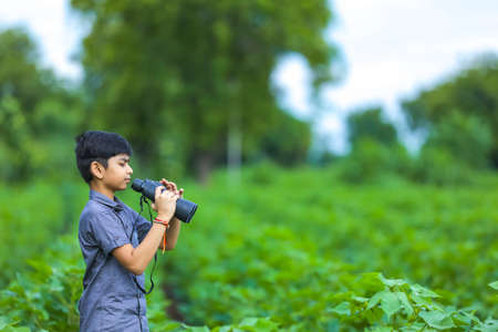 little Indian boy enjoys in nature with binocularsの写真素材
