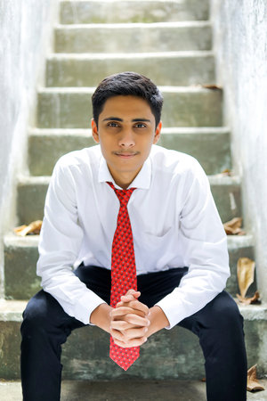 handsome Indian young boy wearing white shirt and red tieの写真素材
