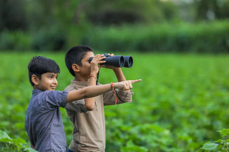 Tow little Indian boy enjoys in nature with binocularsの写真素材