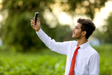 young indian man clicking selfie with mobileの写真素材