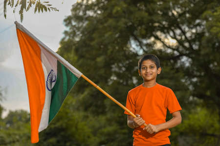 little indian child holding, waving or running with Tricolour flagの写真素材