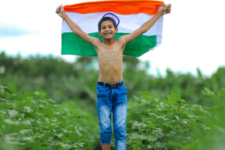 Indian child celebrating Independence or Republic day, Cute little Indian child holding, waving or running with Tricolour flag with greenery in the background,の写真素材